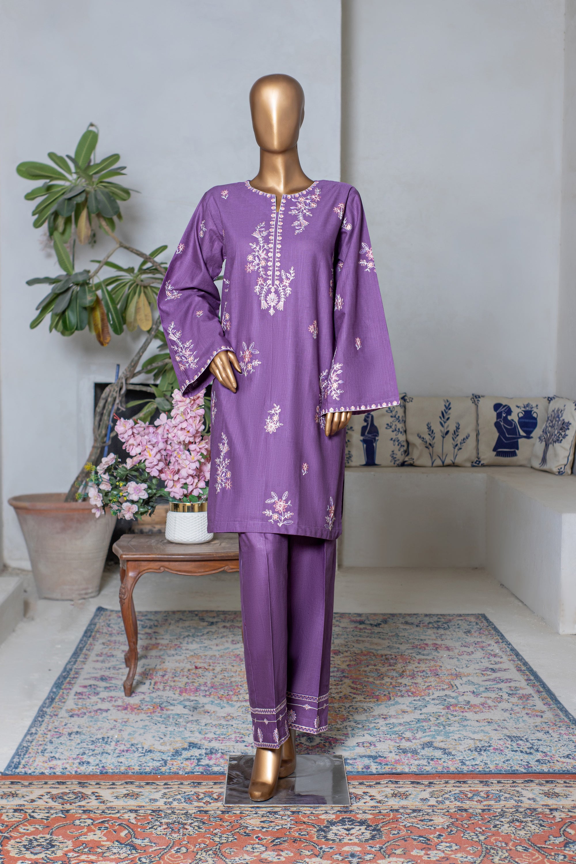 Purple embroidered outfit on a mannequin in a room with a couch and plants.